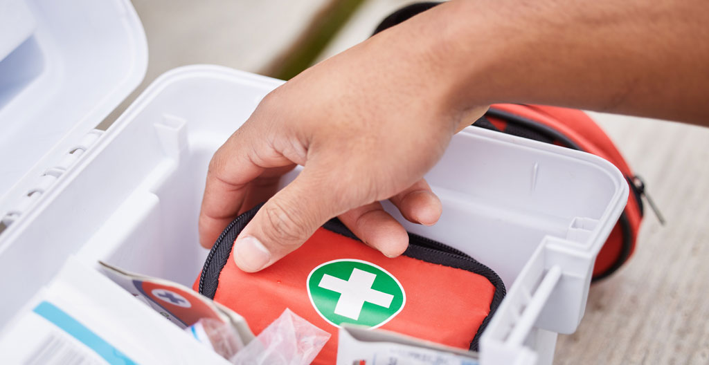 Contenu d'une trousse de secours professionnelle disposée sur une surface de chantier avec compresses, bandes et antiseptique