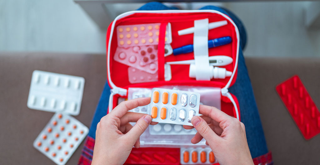Responsable sécurité vérifiant les dates de péremption des produits d'une trousse de secours en entreprise